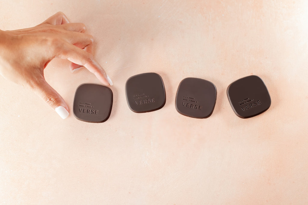 dark chocolate medallions against pink background with hand
